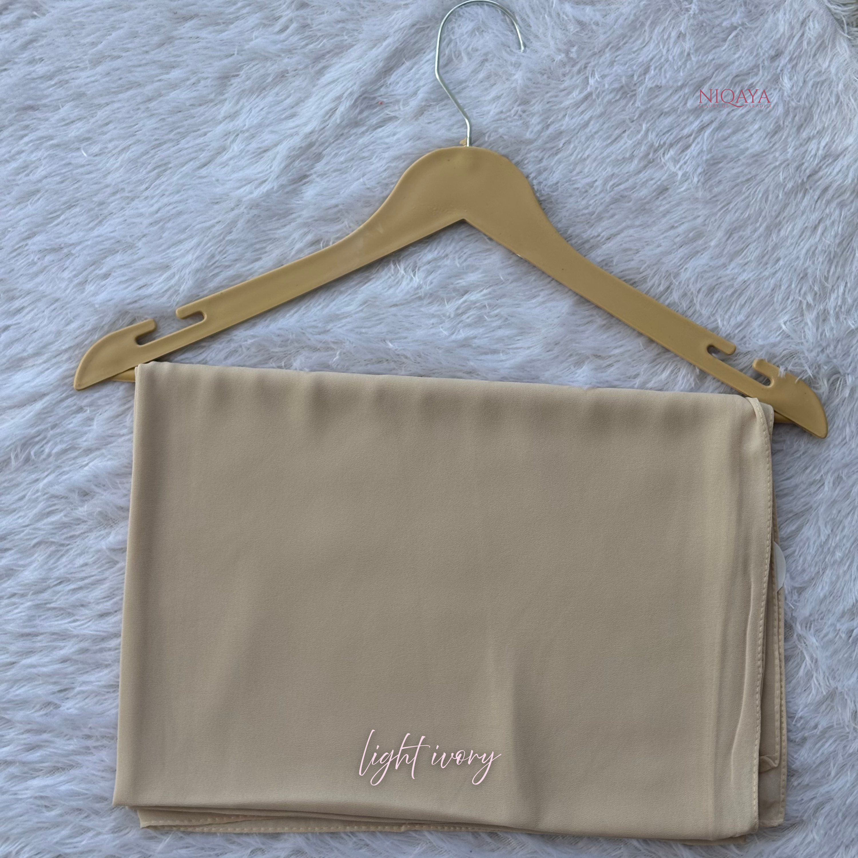 Folded beige fabric with 'light ivory' text on a hanger against a textured gray background