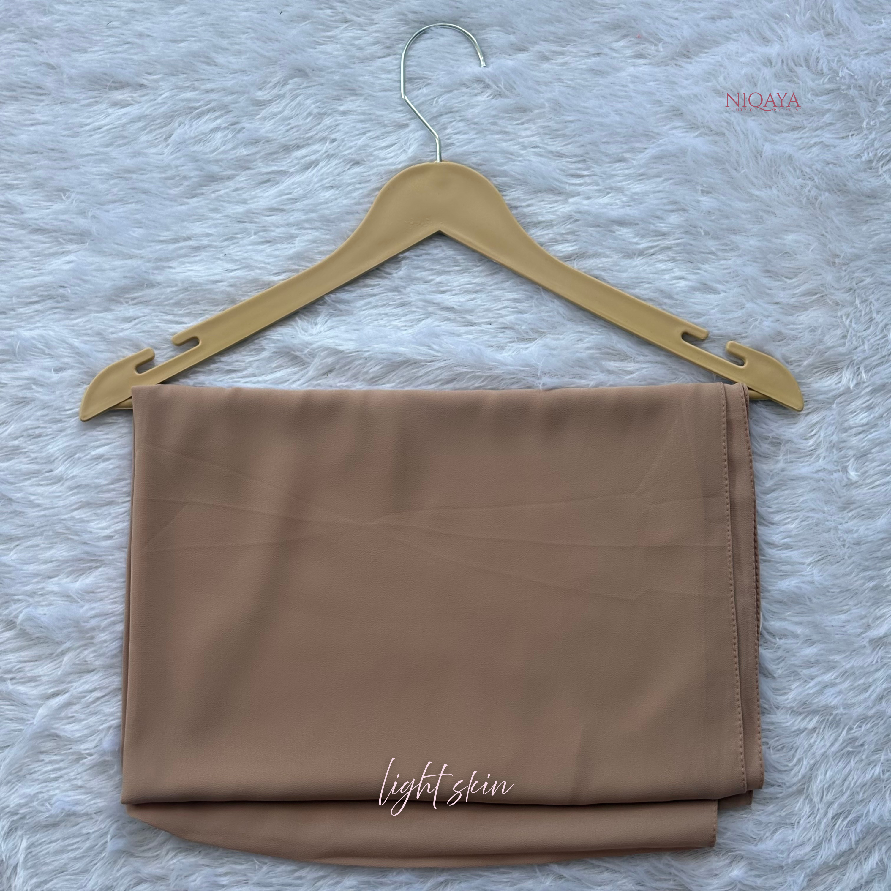 Folded brown fabric on a beige hanger against a textured white background