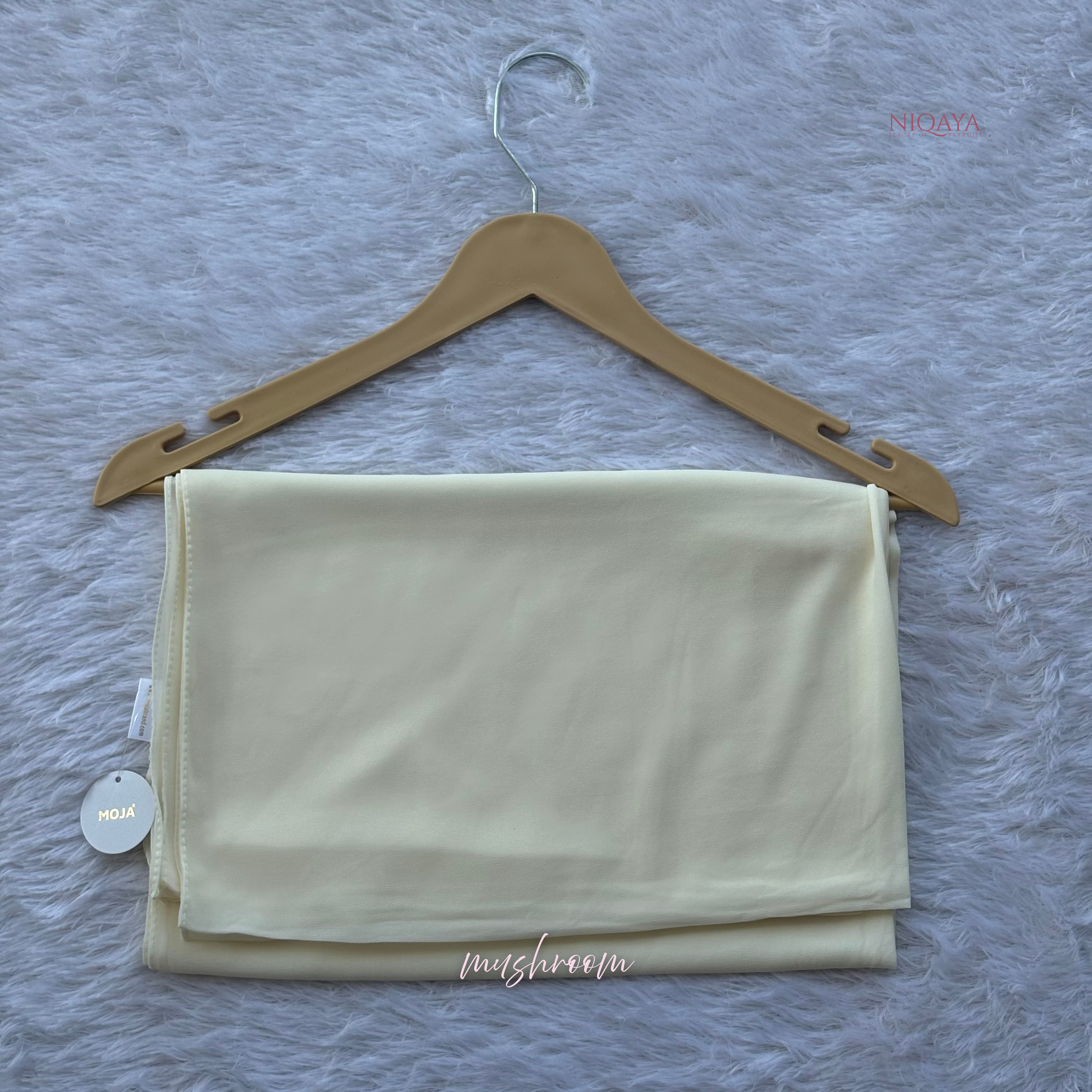 Folded beige fabric on a wooden hanger against a textured gray background