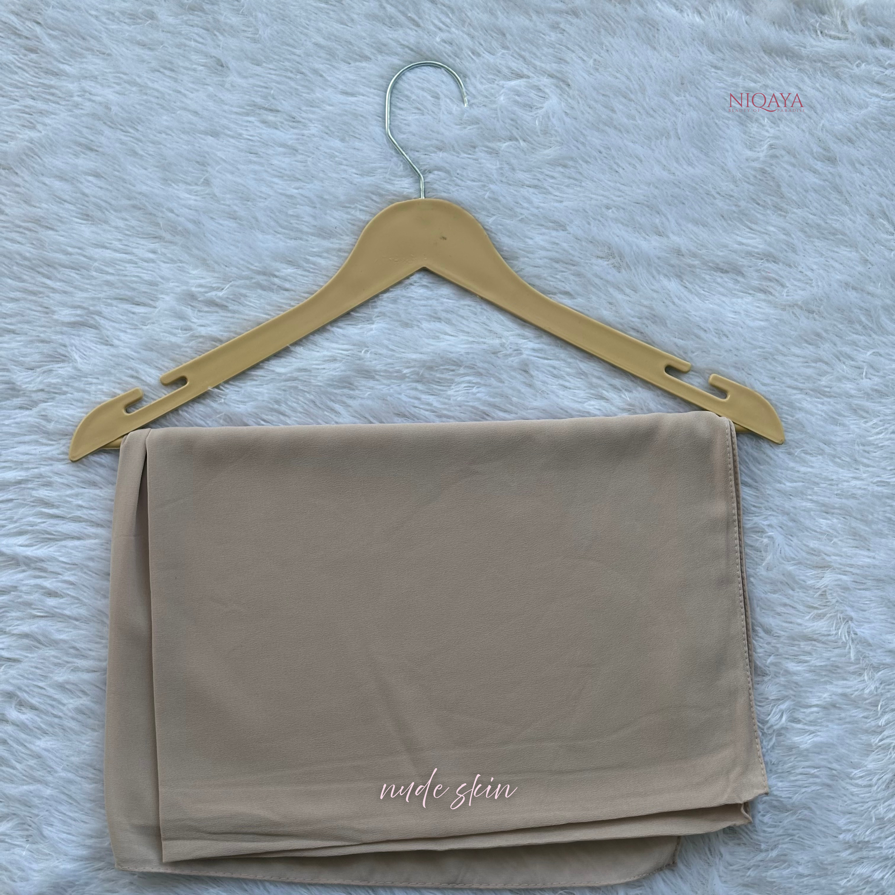 Beige fabric on a gold hanger against a textured gray background