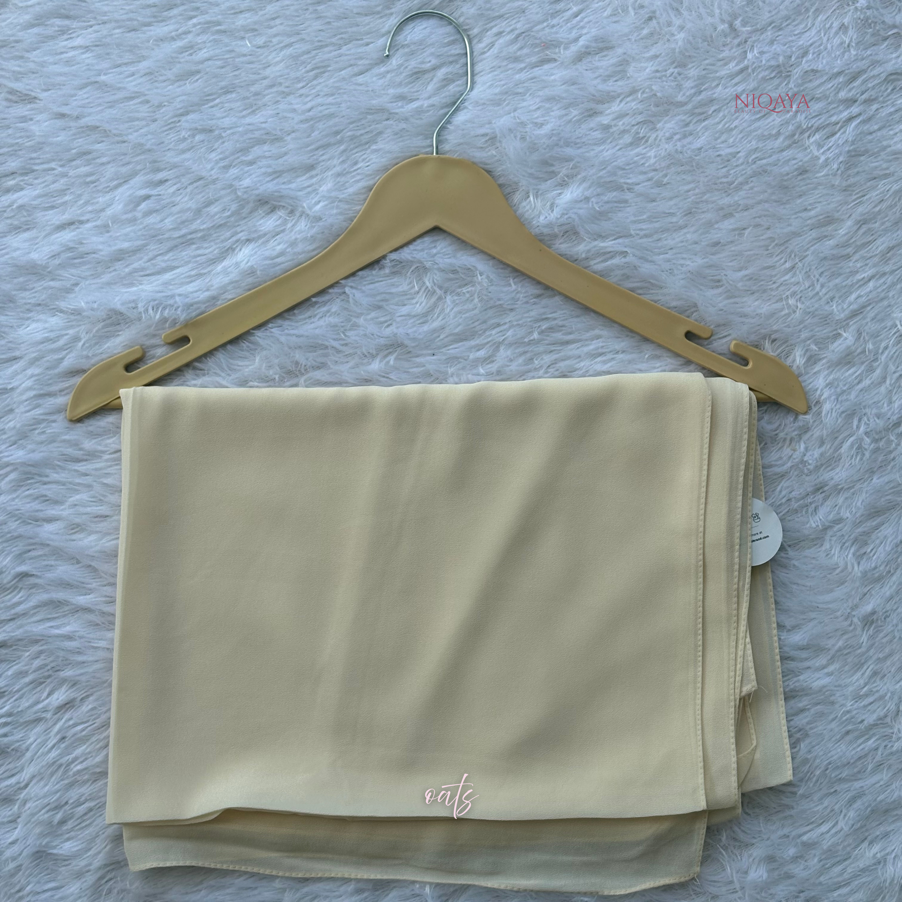 Beige fabric on a hanger against a textured gray background
