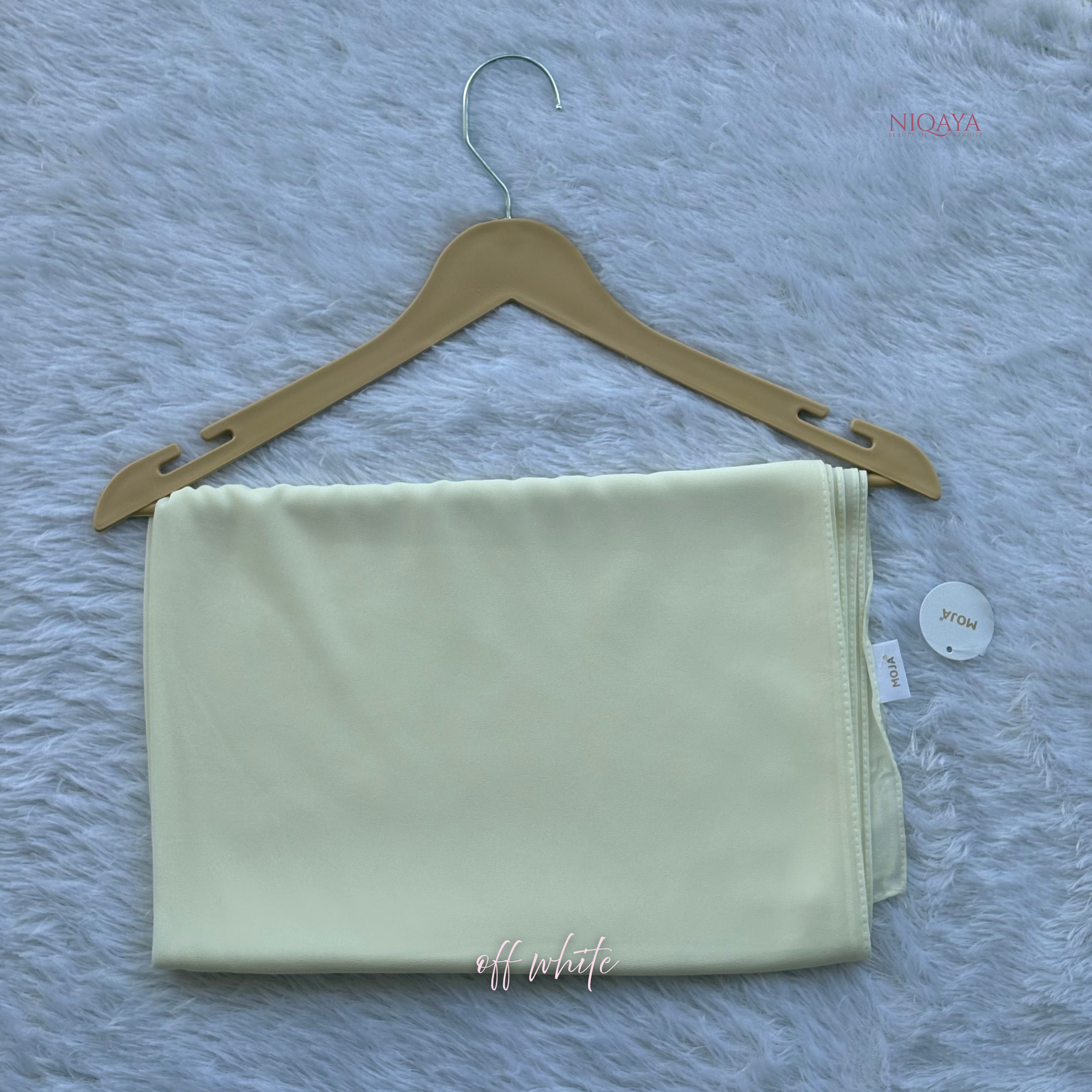 Light green fabric on a wooden hanger with a gray textured background