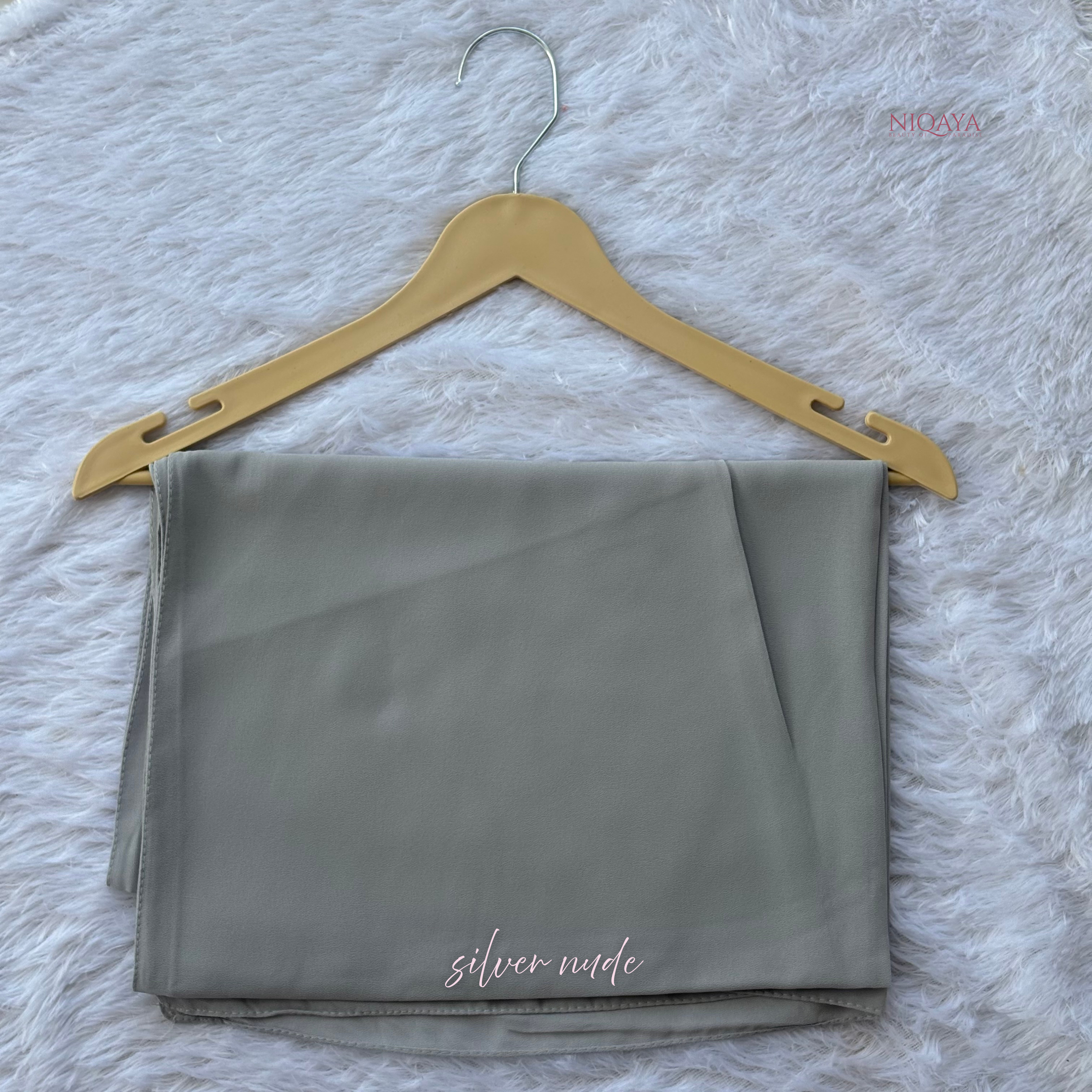 Folded gray fabric on a gold hanger against a textured white background