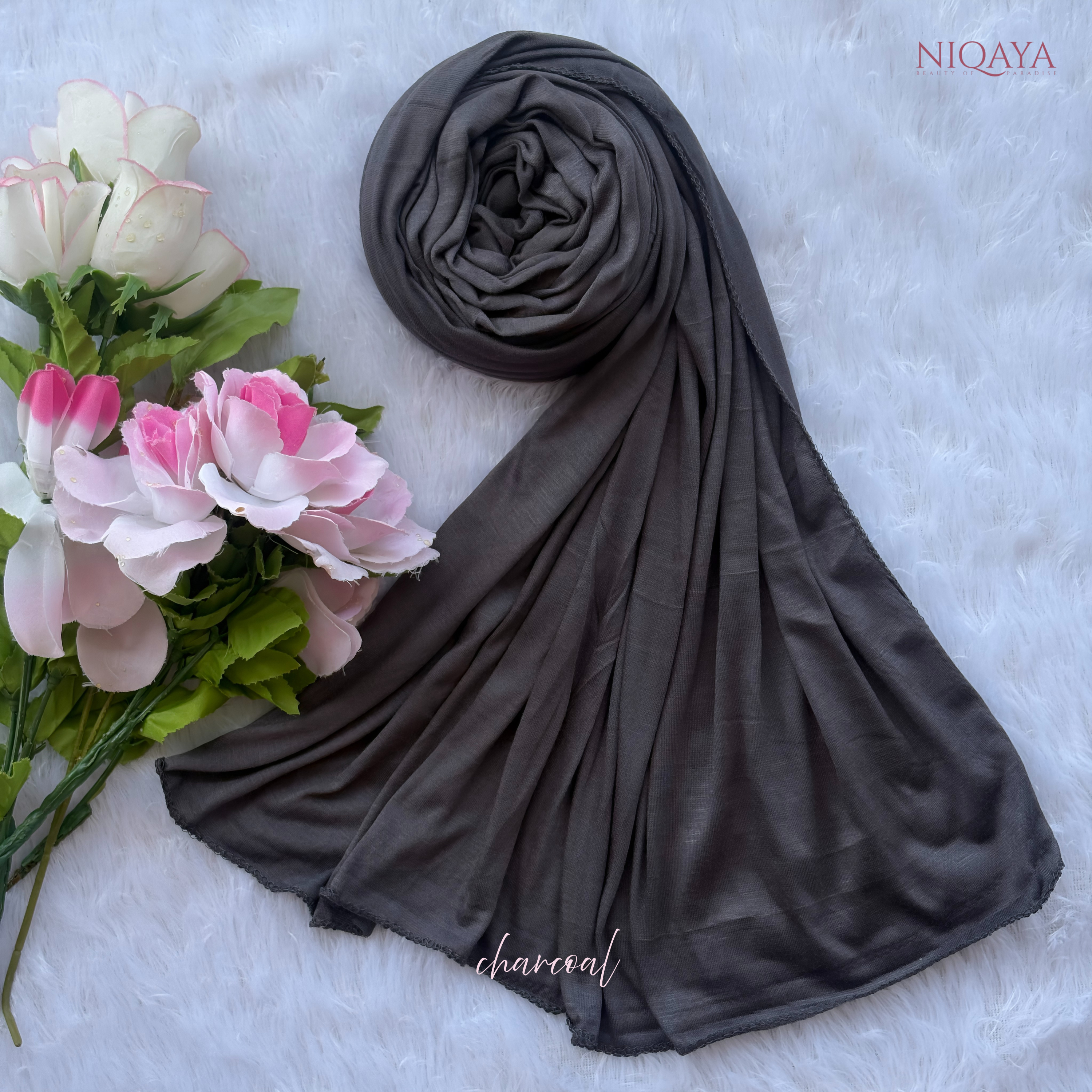 Dark gray hijab with flowers on a light background, featuring the brand 'NIOQAYA'.