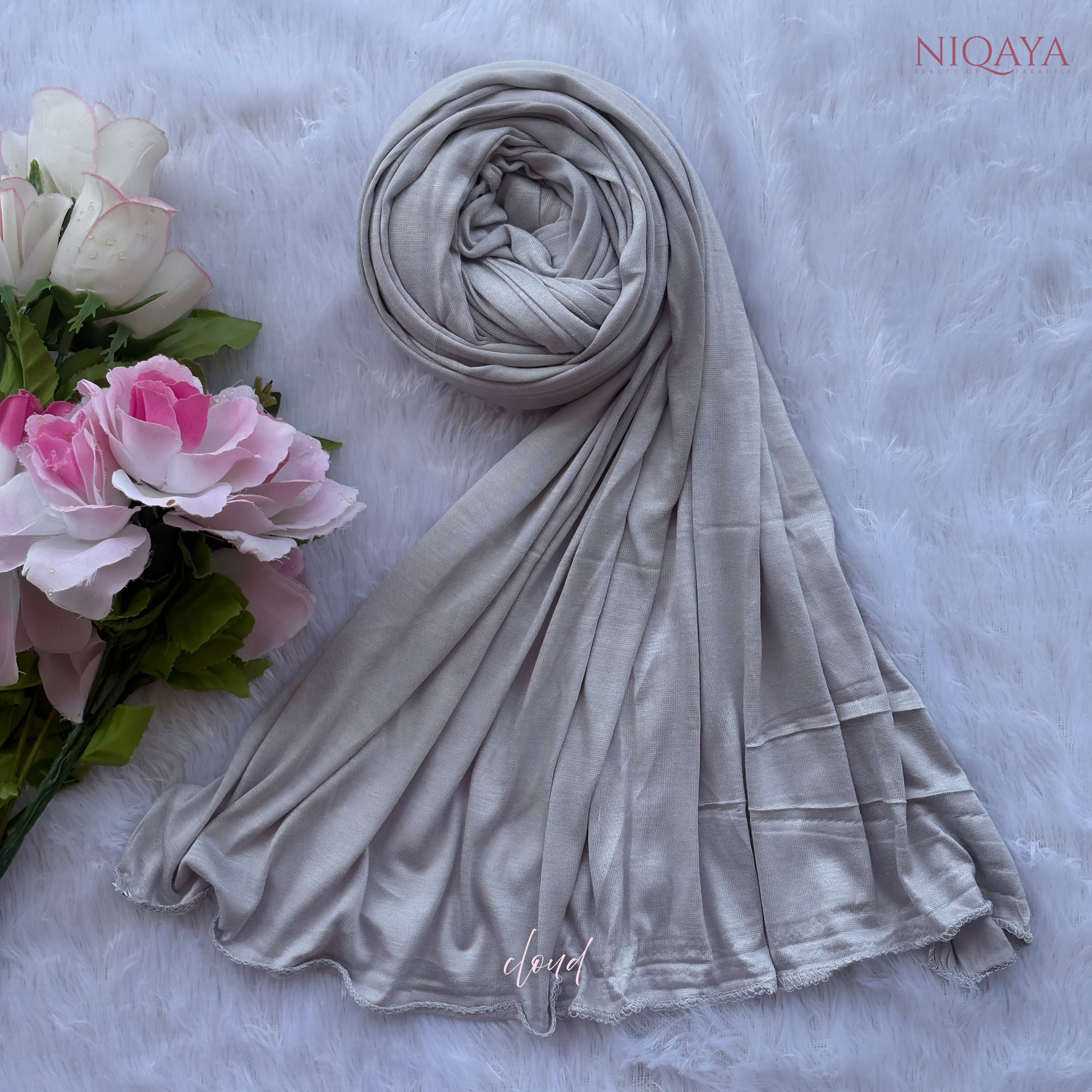 Gray hijab with a floral arrangement on a textured surface, featuring the brand 'Niqaya'.