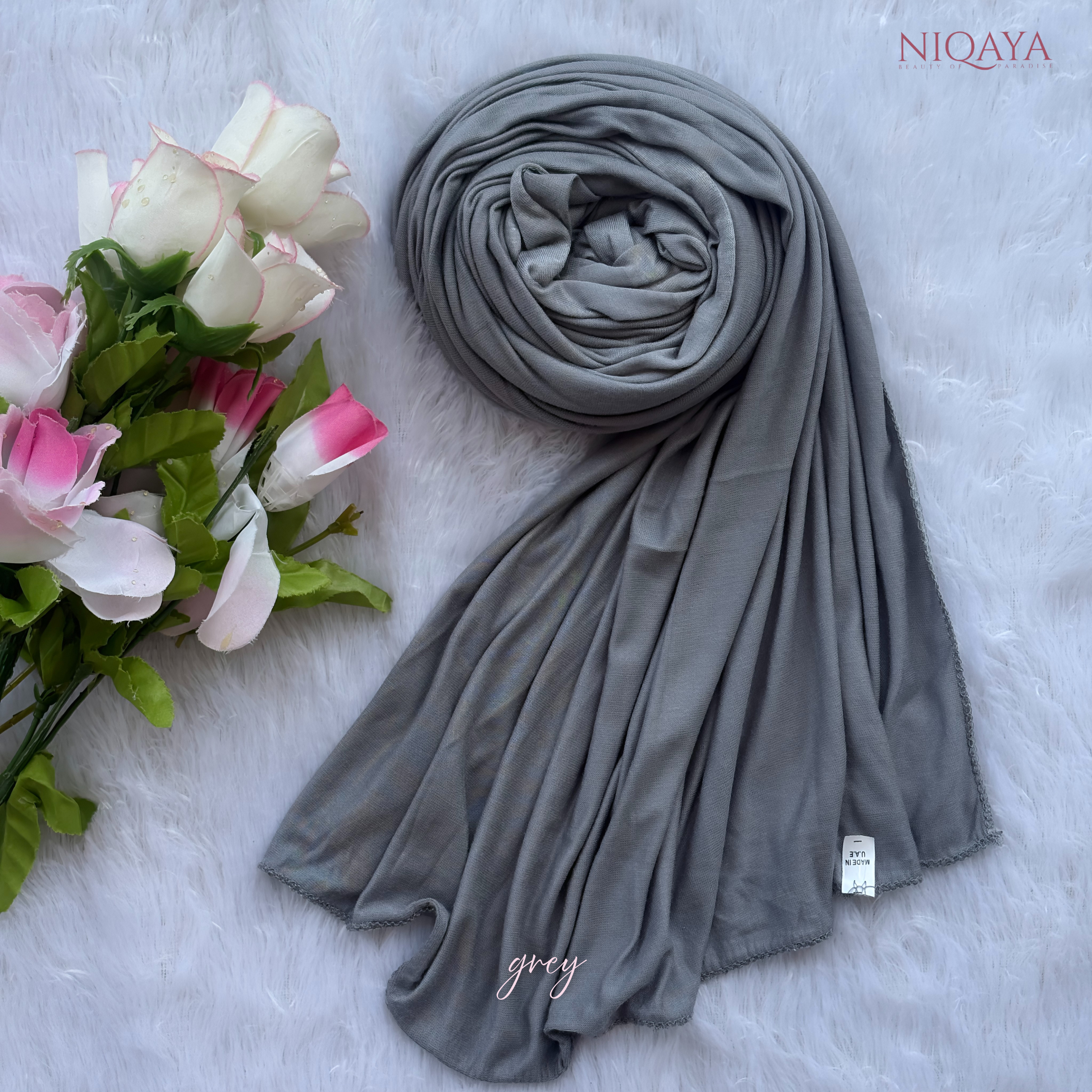 Gray hijab with a bouquet of flowers on a light gray background, featuring the brand 'NIQAYA'.