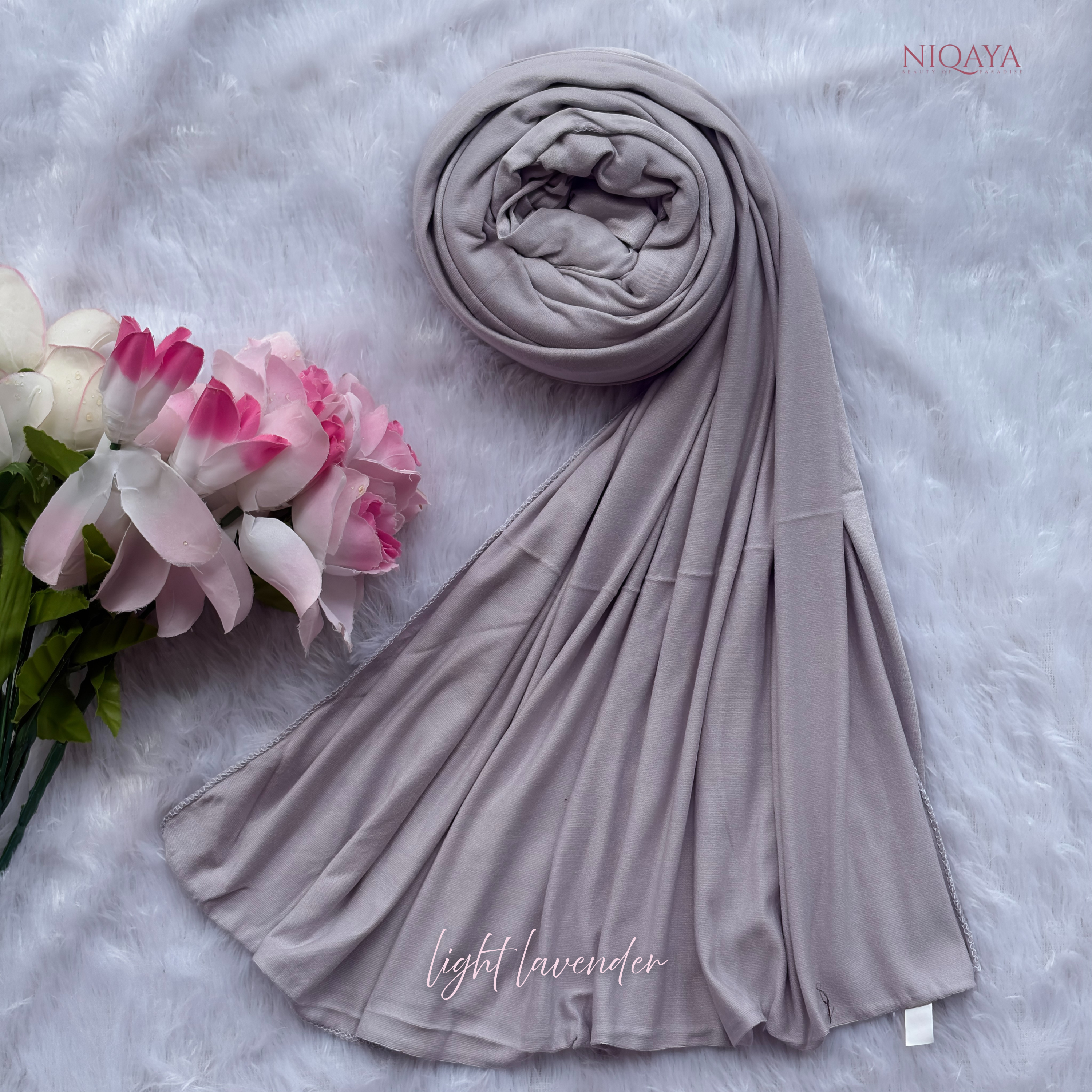 Light lavender hijab with a bouquet of flowers on a textured surface, featuring the brand 'NIQAYA'.