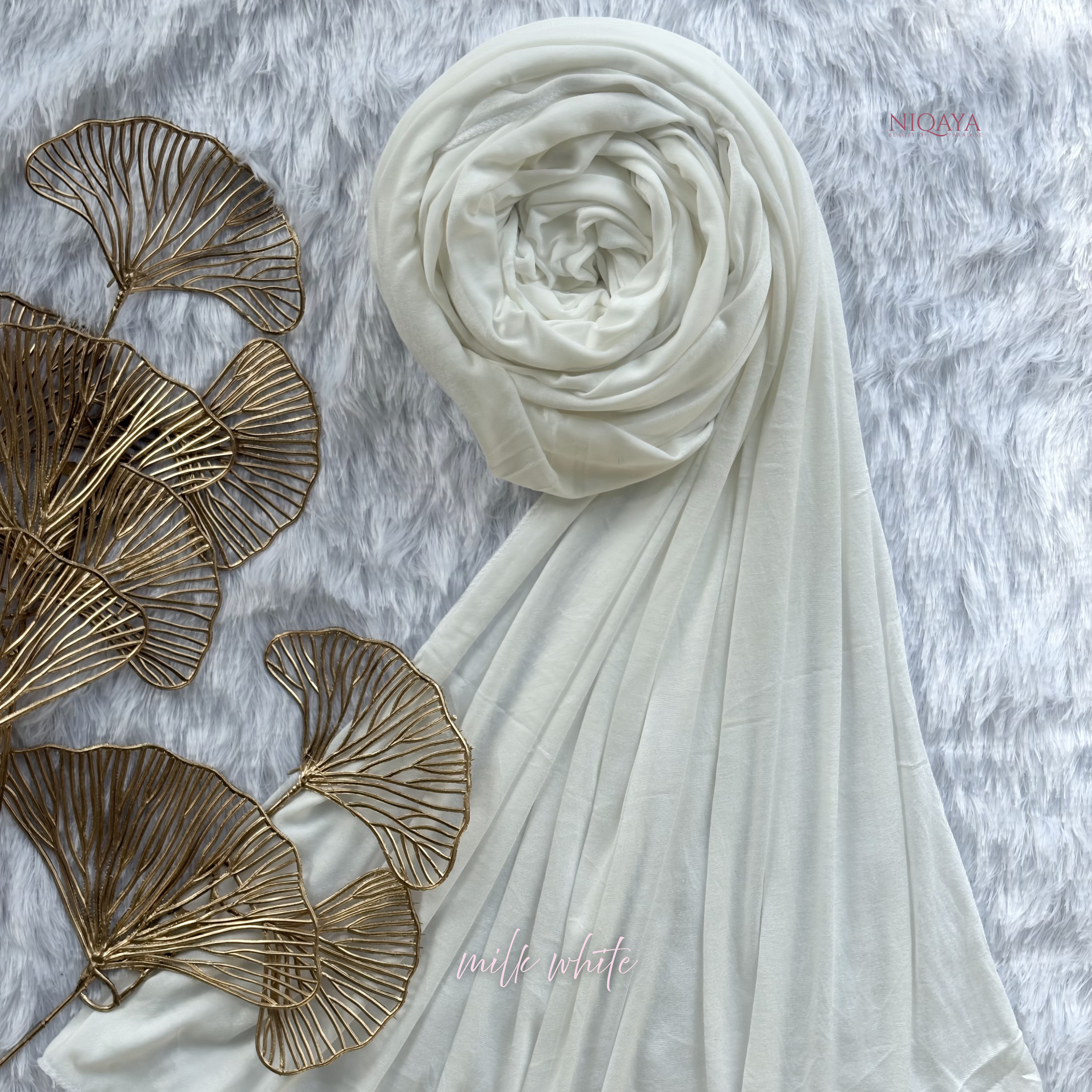 White hijab with gold leaf decorations on a textured surface