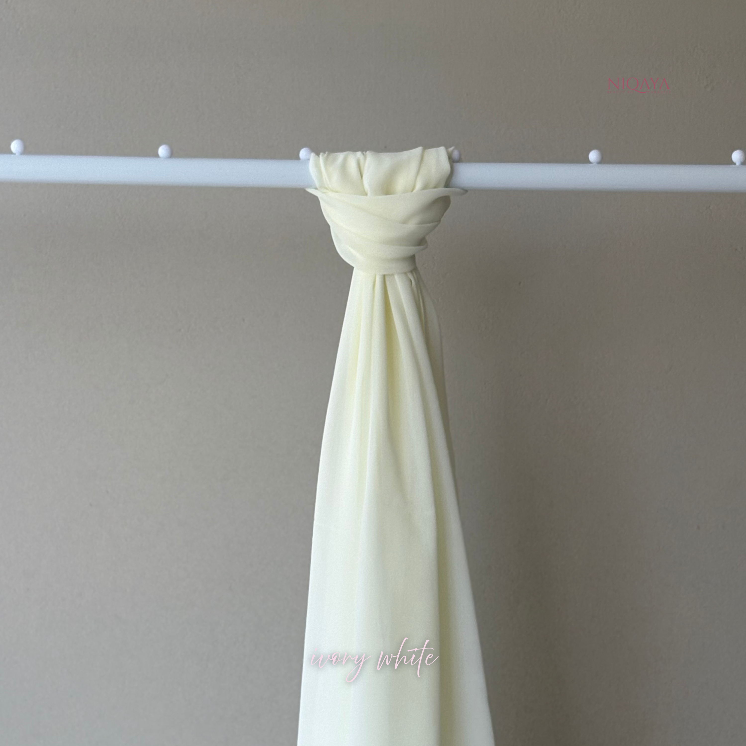 White curtain tied back on a rod against a plain wall with 'White' branding.