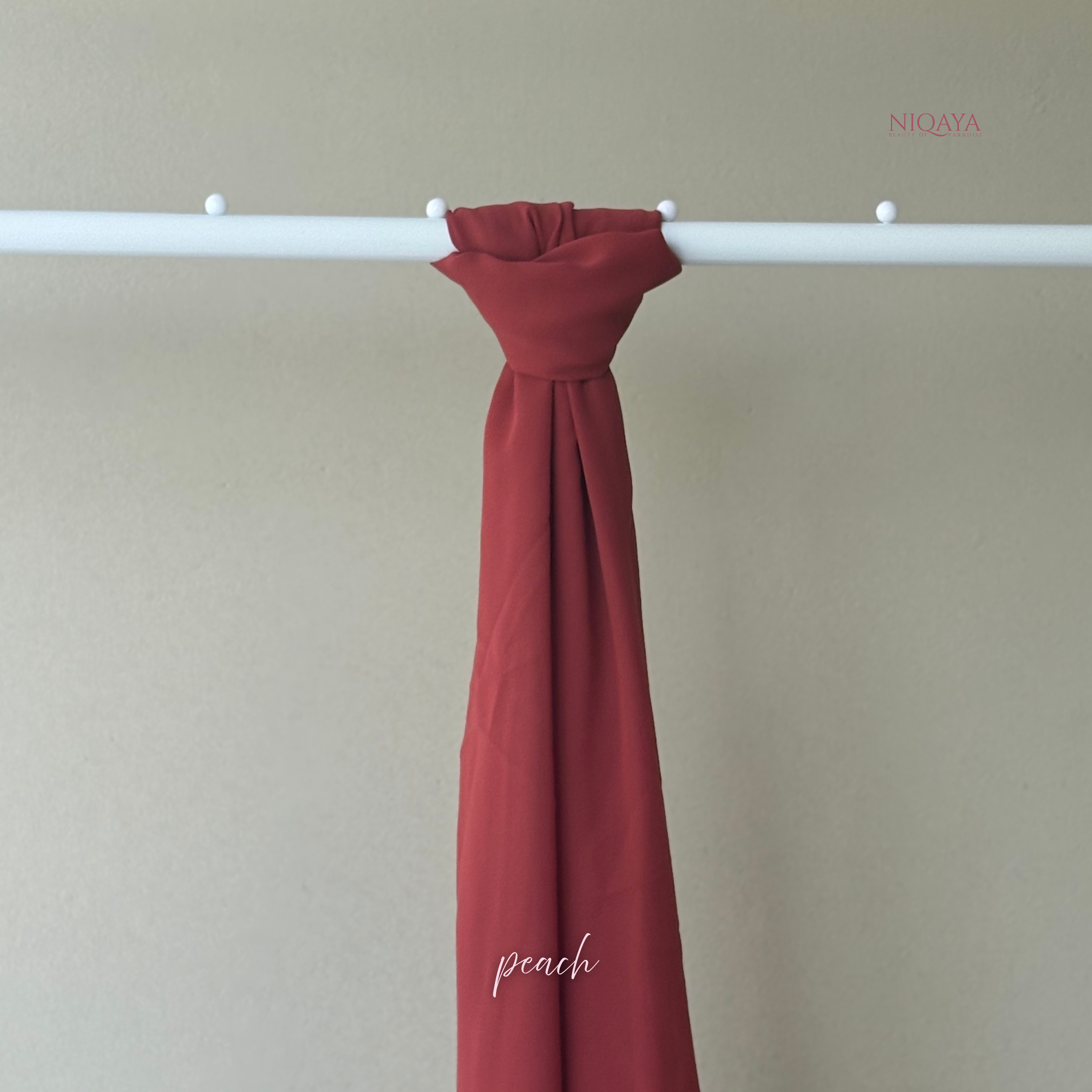 Red fabric swatch on a white rod against a beige wall with 'Niqaya' branding.