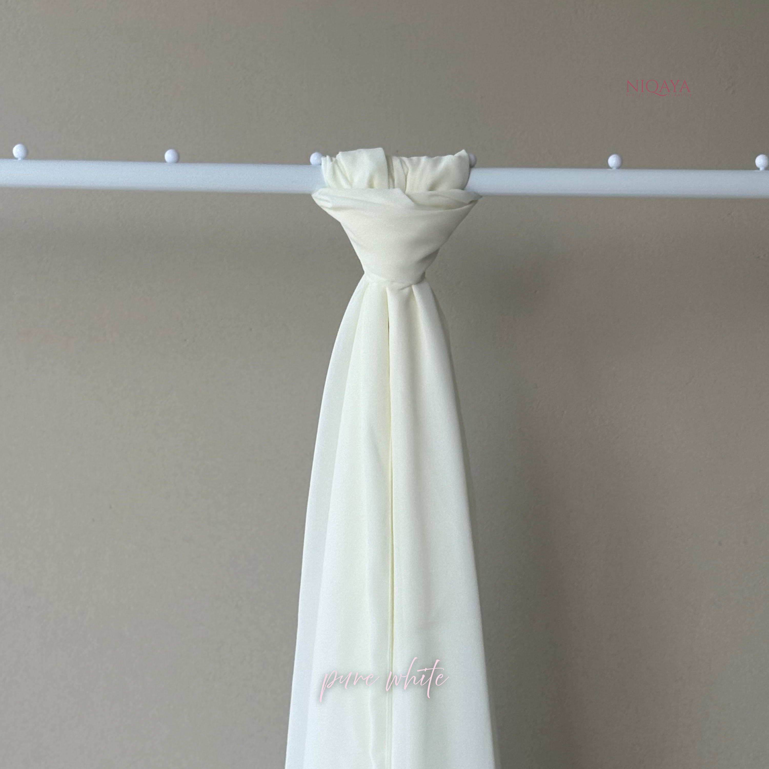 White curtain with a floral tie-back against a plain wall