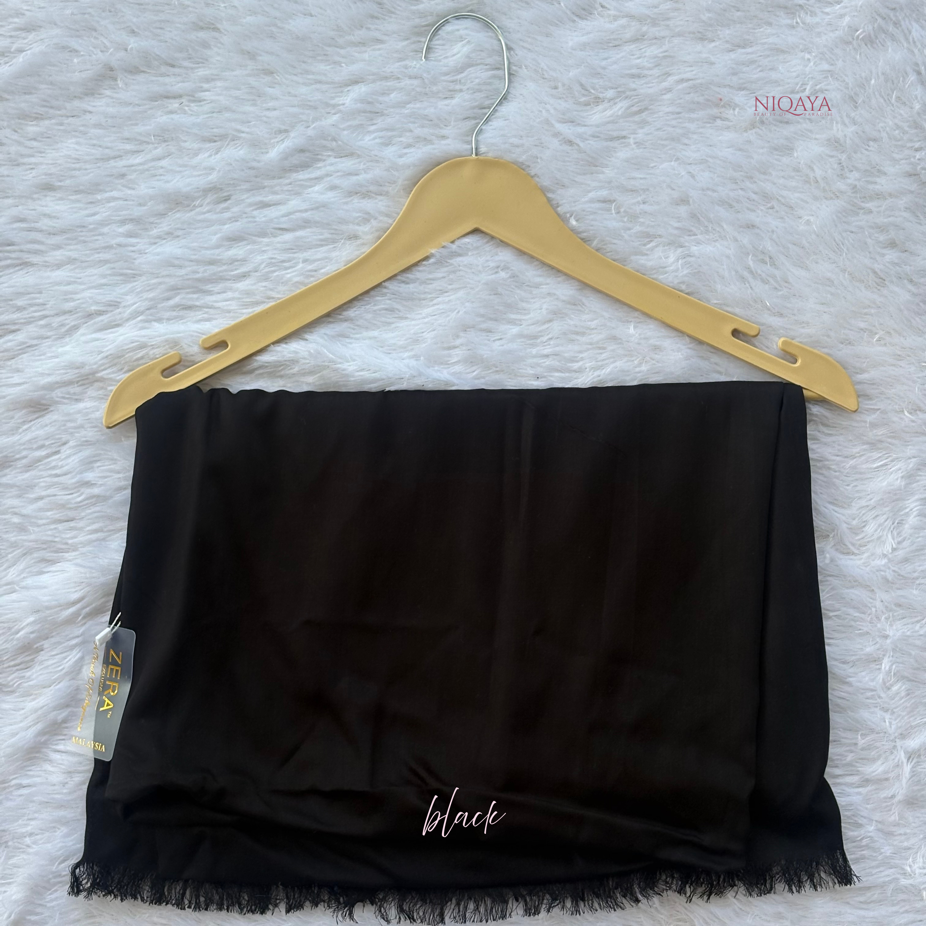 Black strapless top on a hanger with 'NIQAYA' branding on a textured white background.