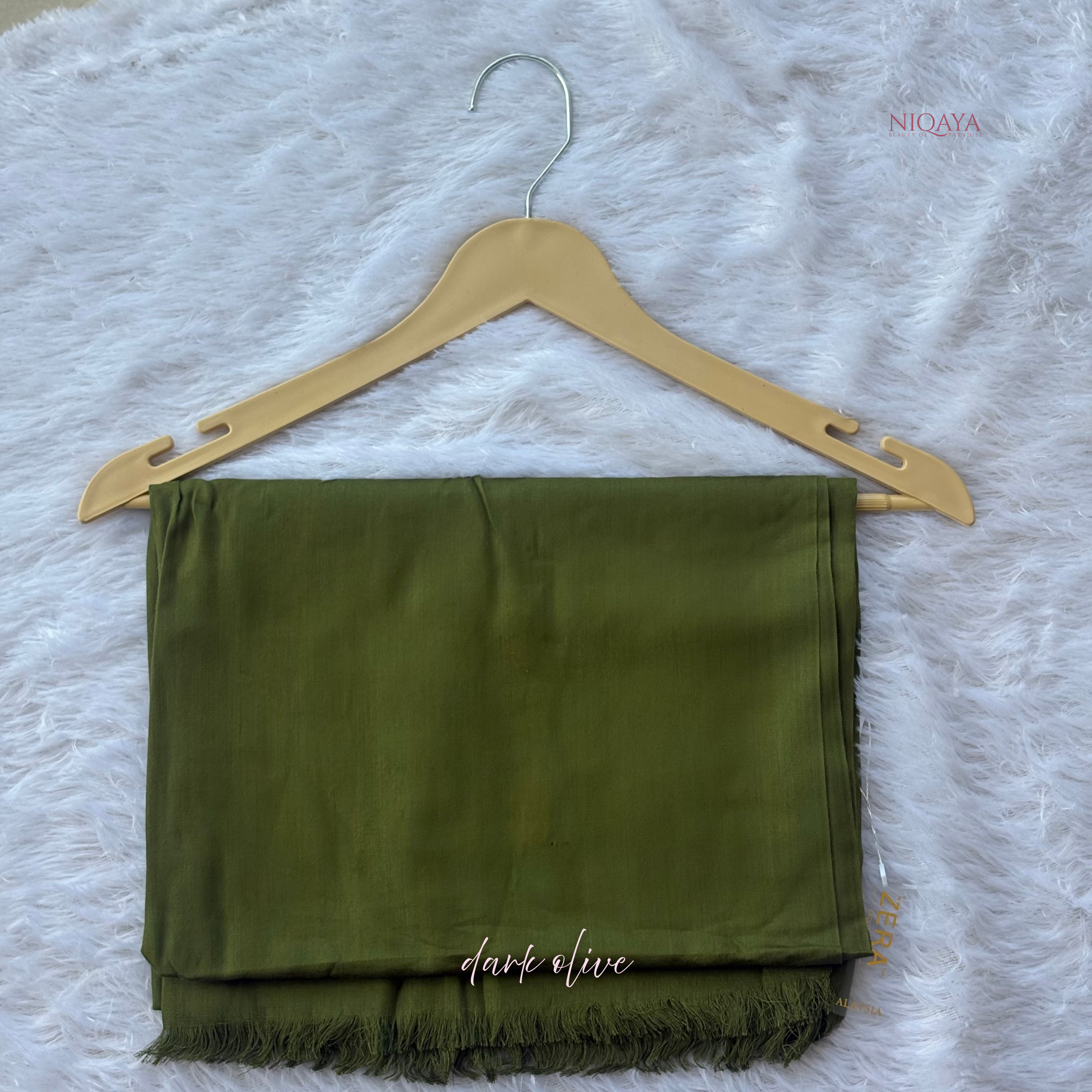 Dark olive green scarf on a wooden hanger against a white textured background