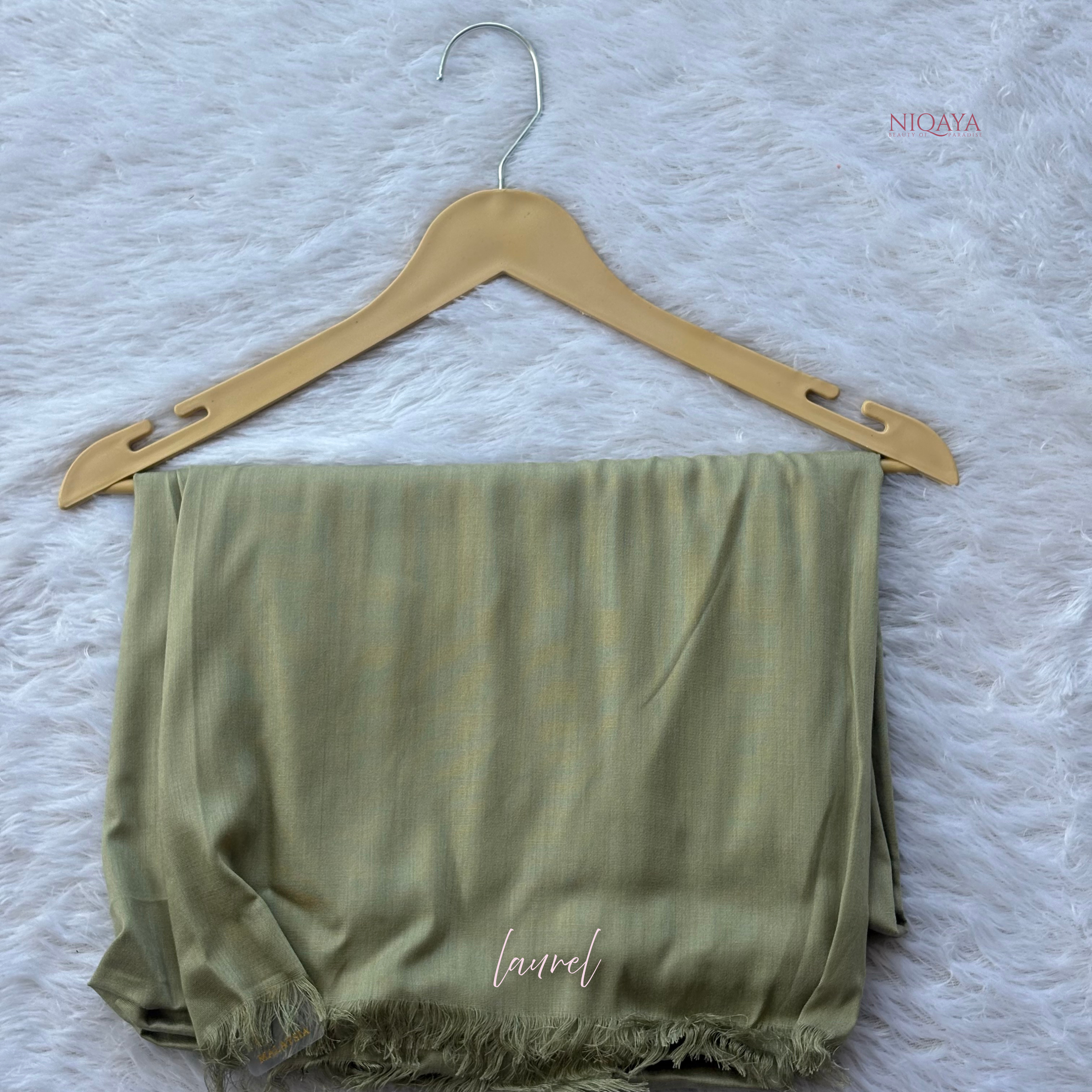 Green scarf with 'laval' text on a wooden hanger against a textured white background