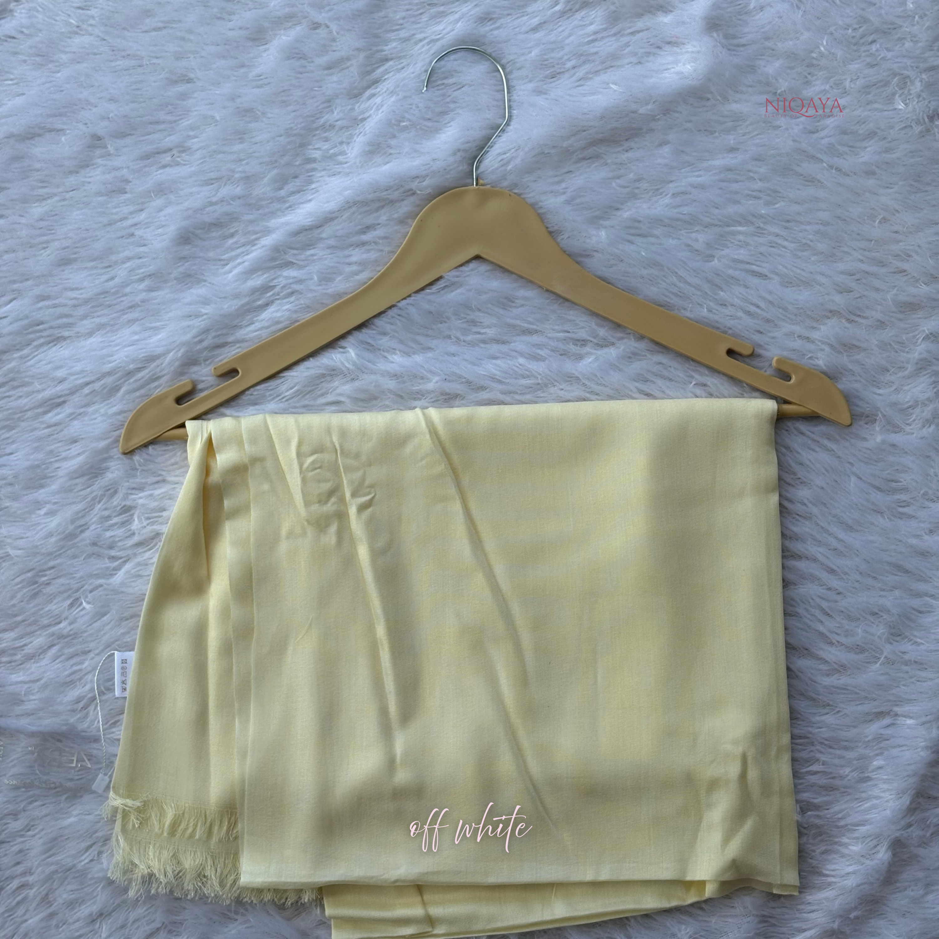 Light yellow shorts on a hanger with 'off white' text on a textured gray background