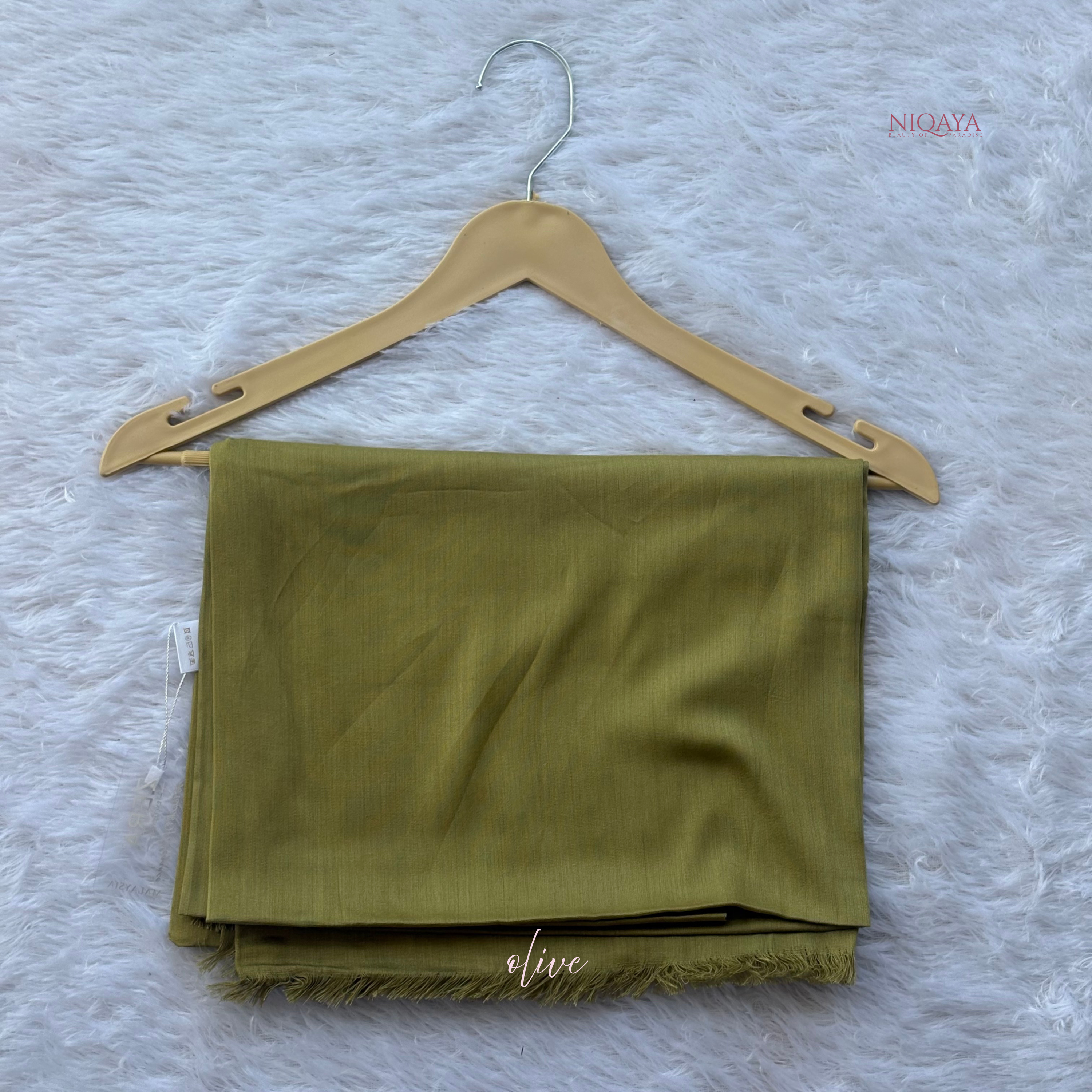 Folded olive green fabric on a wooden hanger against a textured white background