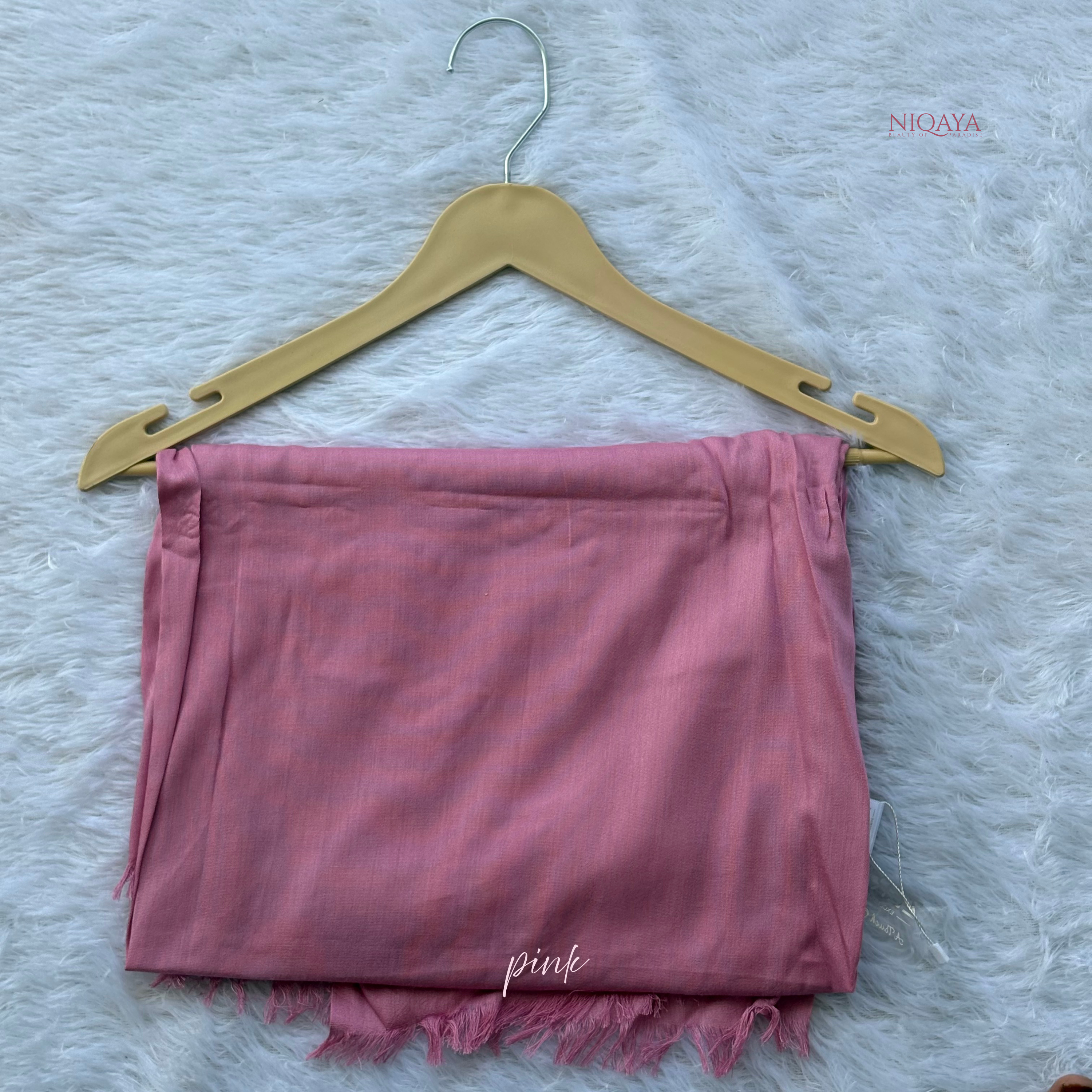 Pink shorts on a hanger with 'NIQAY' branding on a textured white background